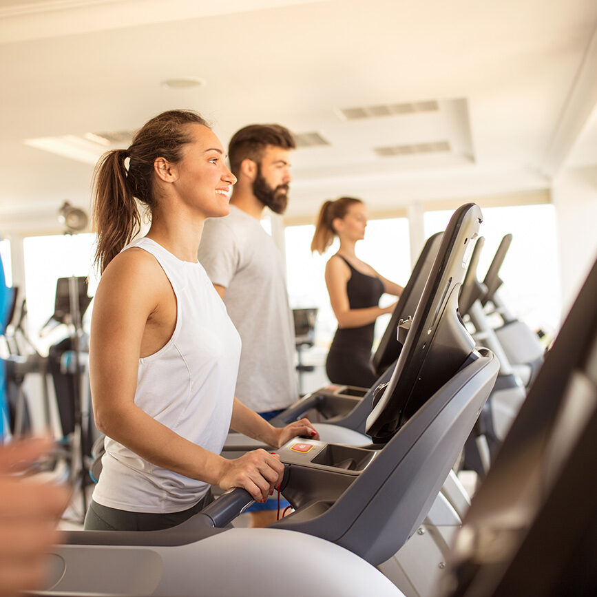 Group of  people in gym or fitness club exercising their legs doing cardio training